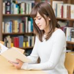 図書館で座って本を読む女子大生