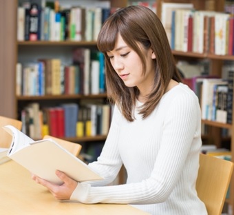 図書館で座って本を読む女子大生