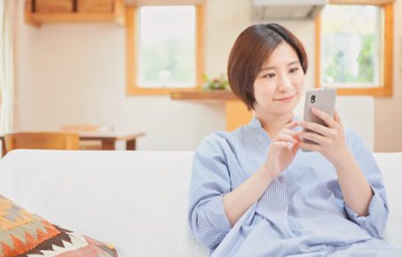 ソファでスマホを見る女性