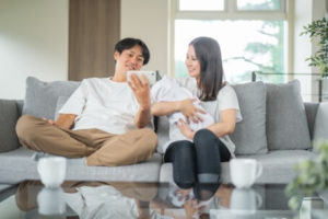 部屋でスマホを使う赤ちゃんを抱く男女