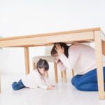 机の下に避難する親子