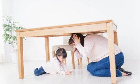机の下に避難する親子