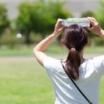 水のペットボトルで頭を冷やす女性