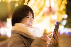 冬の街中でスマートフォンを持つ女性