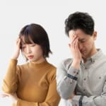 頭を押さえて悩む男女2人