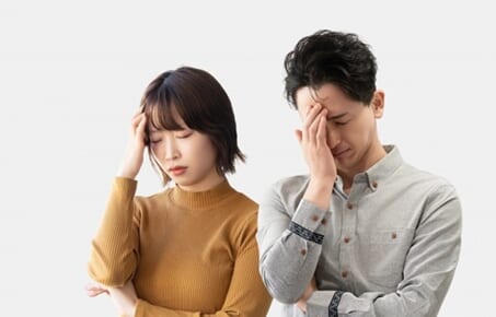 頭を押さえて悩む男女2人