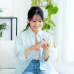 部屋でスマホを操作する女性