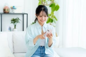 部屋でスマホを操作する女性