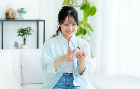 部屋でスマホを操作する女性