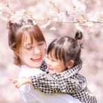 満開の桜の中で娘を抱く母親