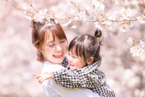 満開の桜の中で娘を抱く母親