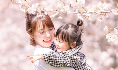 満開の桜の中で娘を抱く母親