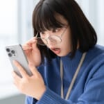 スマホの画面を見て驚く女性