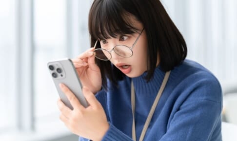 スマホの画面を見て驚く女性