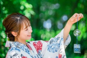 緑の中で風鈴を持つ浴衣姿の日本人女性