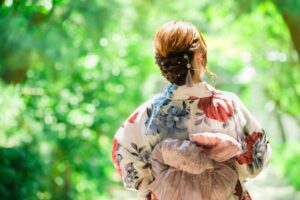 緑の中を歩く浴衣を着た女性の後ろ姿