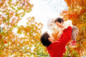 紅葉の中で遊ぶ母親と男の子