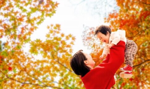 紅葉の中で遊ぶ母親と男の子